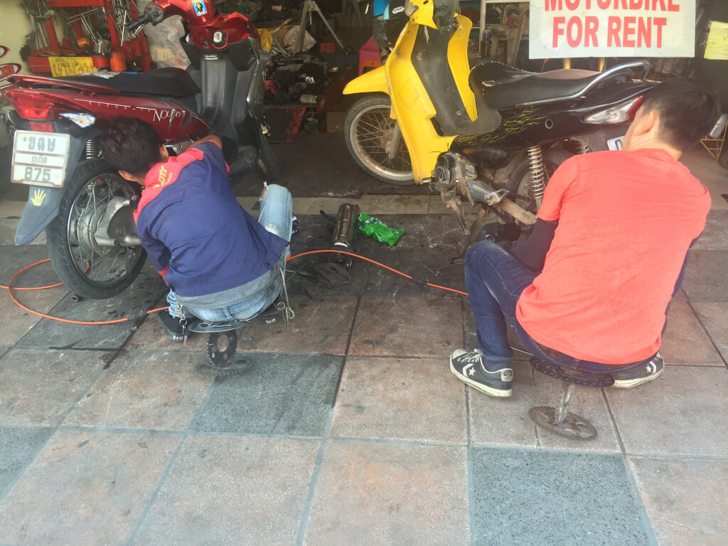The scooter repair guys working in the garage.